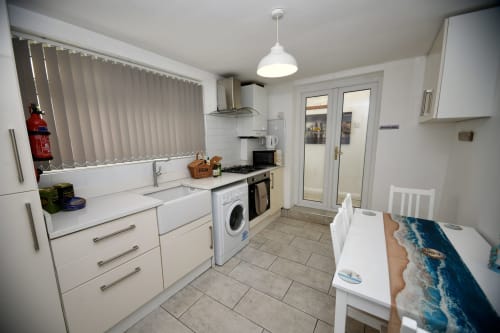 Modern kitchen and dining area in The Lower Deck apartment at Love Short Stays, South Shields with white cabinetry and dining