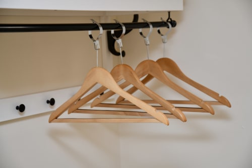 Wooden hangers hanging on black rod with silver hooks in The Lower Deck apartment at Love Short Stays, South Shields