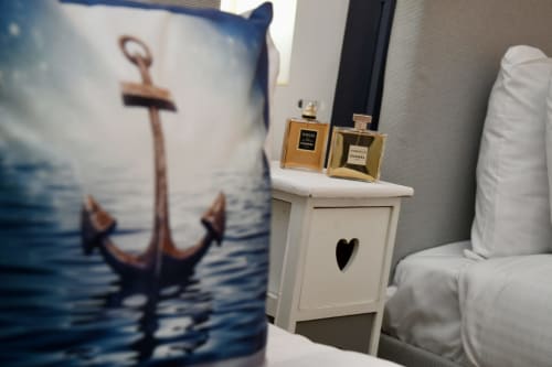 Nautical bedroom decor at Love Short Stays featuring anchor pillow, white nightstand with heart cutout, and luxury perfume