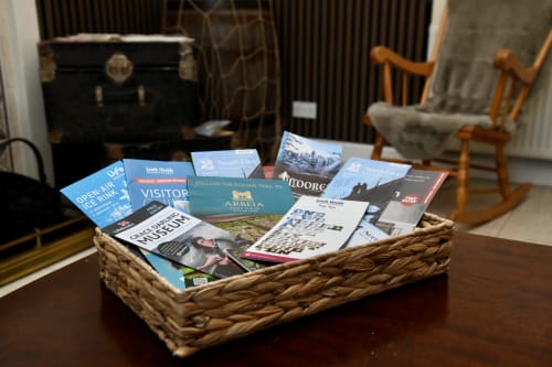 Woven basket filled with visitor guides and travel brochures on wooden desk in Love Short Stays hotel room, South Shields