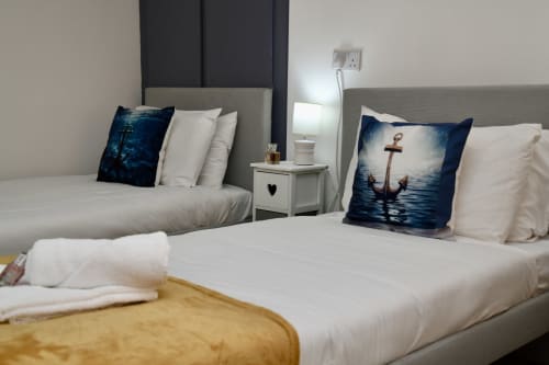 Modern twin bedroom at Love Short Stays with nautical-themed pillows, crisp white linens, and contemporary furnishings in
