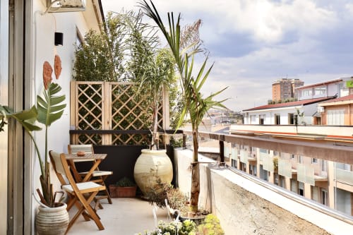 Terrazza sul tetto di Tagasuites a Catania con sedute in legno, piante in vaso, grigliato e vista sulla città
