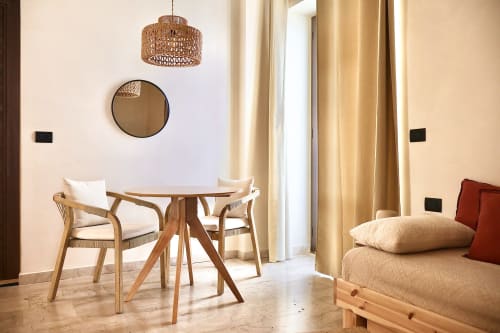 Suite Deluxe di Tagasuites a Catania con tavolo in legno, lampada a sospensione intrecciata, specchio rotondo e letto confortevole