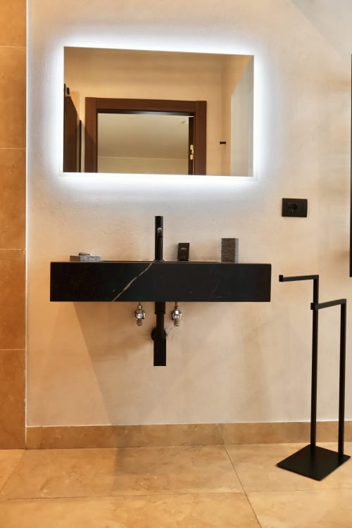 Moderno bagno con lavabo in marmo nero, specchio illuminato e scaldasalviette a Tagasuites Catania