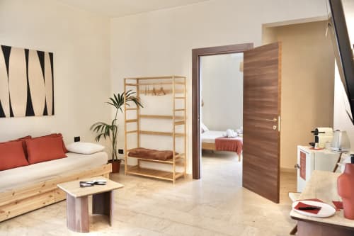 Suite Deluxe Tagasuites 109 a Catania: camera moderna con arredamento in legno, pareti color crema, dettagli rossi e layout aperto