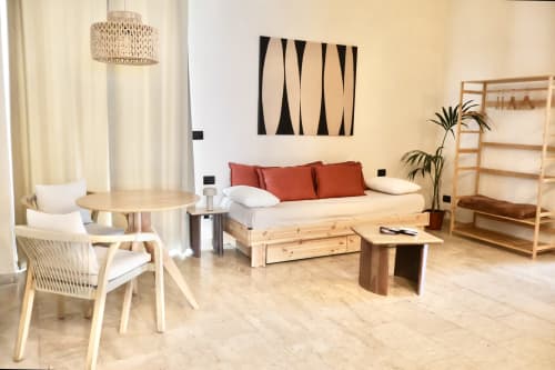 Suite Deluxe moderna presso Tagasuites Catania con mobili in legno chiaro, divano color crema con cuscini ruggine e vista sulla città