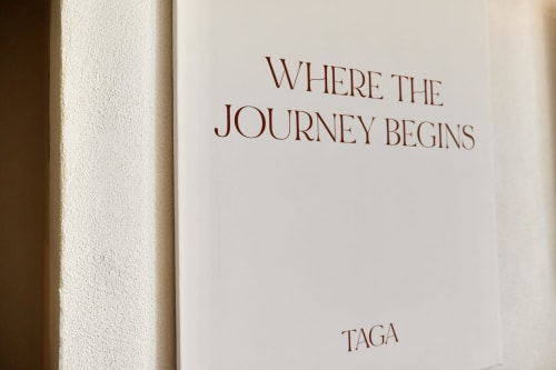 Pagina di libro con la scritta 'Where the Journey Begins' e il marchio Taga presso Tagasuites Catania