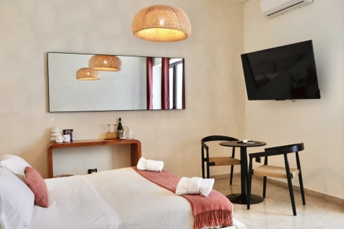Modern junior suite at Tagasuites Catania with bed, woven pendant lights, wall-mounted TV, and work seating area