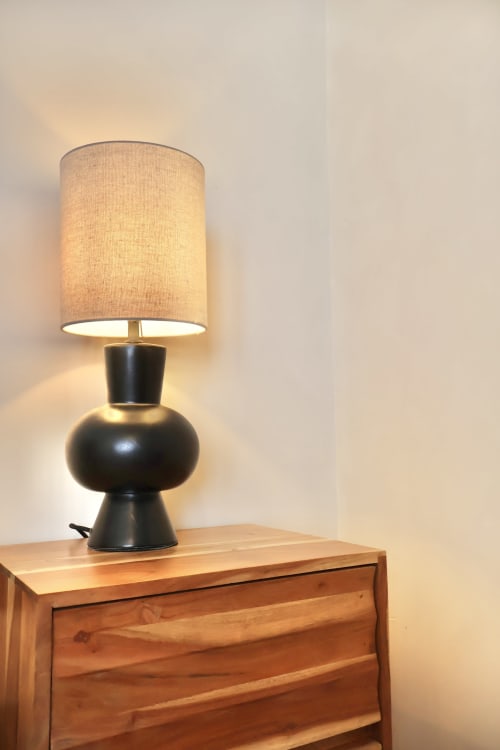 Modern black table lamp with beige linen shade on wooden nightstand at Tagasuites hotel in Catania