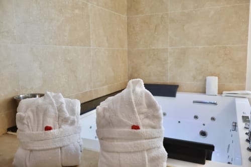 Luxury bathroom with whirlpool tub at Tagasuites, Catania. Rolled towels with rose detail beside modern jacuzzi spa
