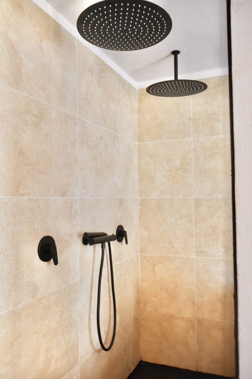 Modern shower area at Tagasuites Catania with dual rainfall showerheads, beige marble tiles, and black fixtures