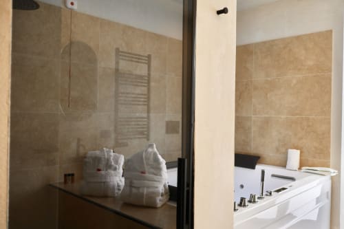 Modern bathroom with glass shower enclosure, white towels, and spa tub at Tagasuites Catania junior suite