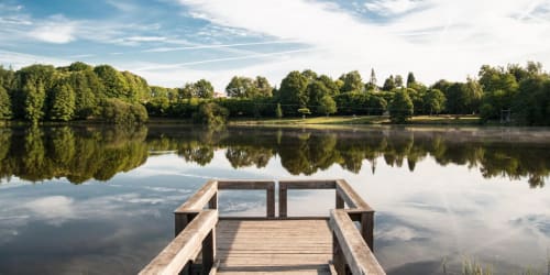 Ponton en bois s'avançant dans le lac calme aux rives boisées, Domaine de Châlus-Chabrol à Châlus, France