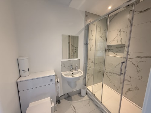 Modern bathroom at Fishergate Residences Preston with marble-effect tiles, glass shower enclosure, and white fixtures