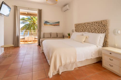 Camera Suite con vista mare presso Villa Bina Sea Hotel, balcone fronte mare, biancheria bianca, testata in legno e pavimenti in cotto