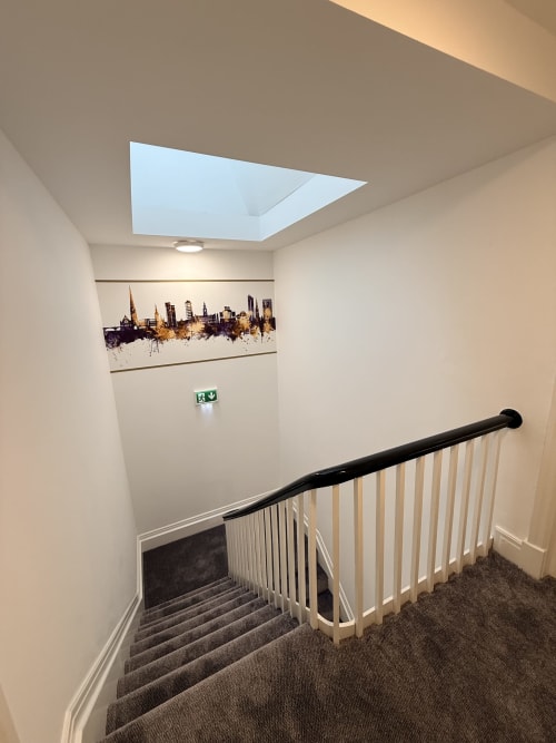 Modern stairwell at Fishergate Residences Preston with skylight, cityscape artwork, and safety railings