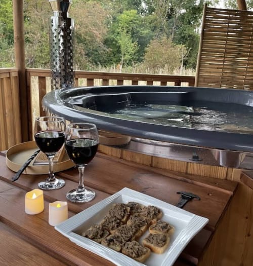 Bain à remous glamping chez You & Me Glamping à Moncontour avec vin et amuse-bouches sur terrasse en bois