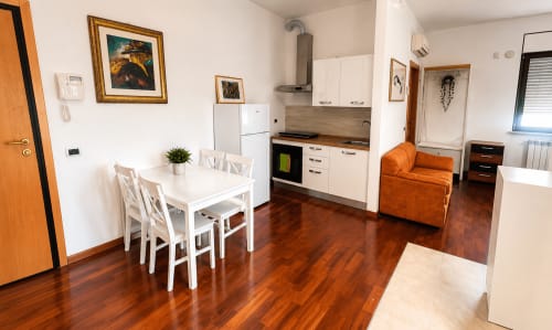 Moderno appartamento a Roma con cucina aperta, zona living, poltrona arancione e pavimenti in legno