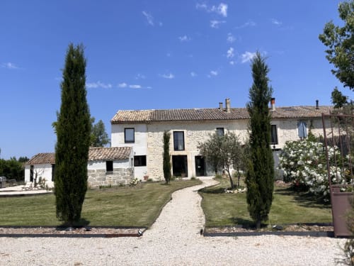 Mas Lafleur à Châteaurenard : maison en pierre avec cyprès, jardins soignés et allée de gravier sous ciel bleu