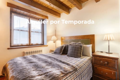 Acogedor dormitorio de montaña con vigas de madera, ropa de cama de cuadros, mesillas de madera y vistas a las montañas en Casau