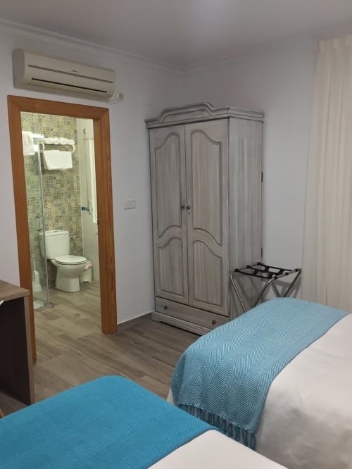 Habitación del Hotel La Posada en Cartagena con dos camas, armario, baño privado con ducha y aire acondicionado moderno