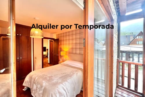 Dormitorio luminoso con cama doble, vistas a la montaña, balcón y muebles de madera en el apartamento de Vielha