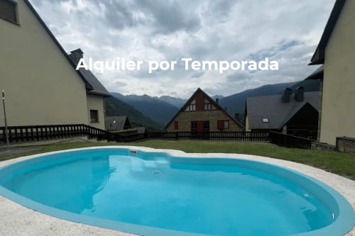 Piscina ovalada en estación de montaña en Vielha e Mijaran con edificios alpinos y cielo nublado