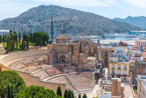 Ruinas del teatro romano en Cartagena con puerto mediterráneo y montañas de fondo