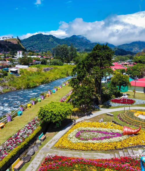 Colorful flower gardens along a river at El Litoral Wellness Retreat in Pennsylvania, with mountains and green landscape.