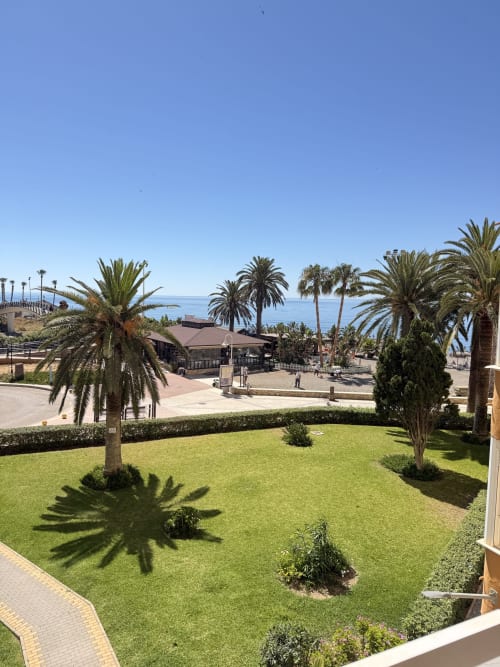 Jardín del apartamento en Algarrobo Costa con palmeras, vista al mar Mediterráneo y piscina compartida