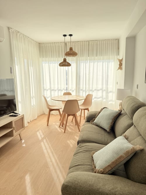 Luminoso apartamento frente al mar en Algarrobo con comedor moderno, sofá gris, lámparas colgantes tejidas y vista al mar