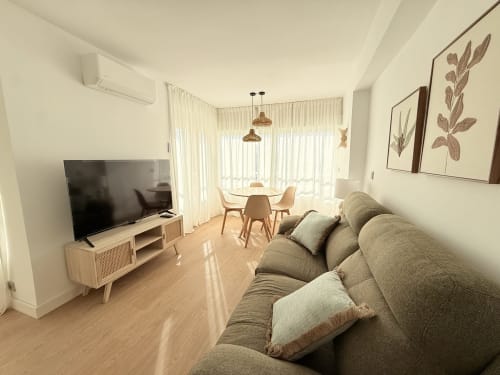 Moderno apartamento con vistas al mar en Algarrobo Costa, sofá gris, TV de pantalla plana, comedor y balcón frente al océano