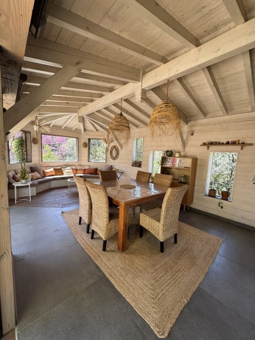 Salle à manger de villa moderne avec poutres en bois, chaises tissées et vue sur le jardin du Domaine d'Olga, Aniane