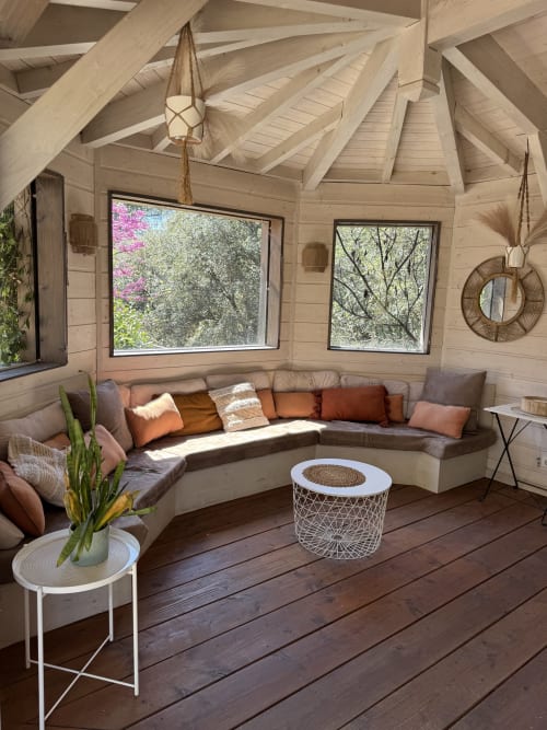 Villa lumineuse d'Olga : salon voûté en bois, canapé sectionnel courbe, vue sur le jardin par grandes fenêtres