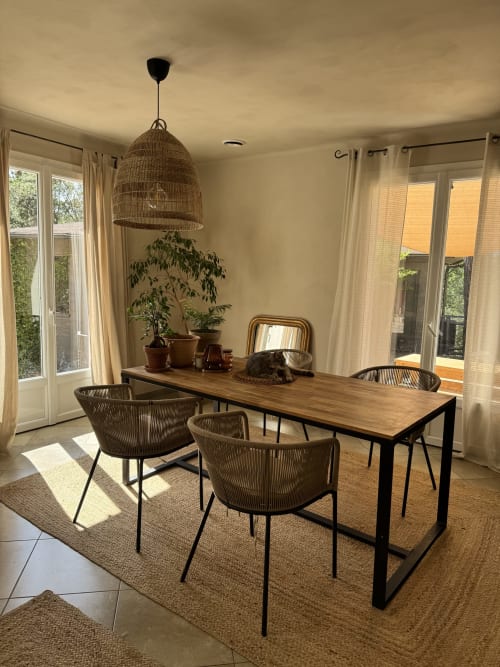 Salle à manger moderne à la Domaine d'Olga avec table en bois, chaises tressées, luminaire suspendu et vue sur le jardin
