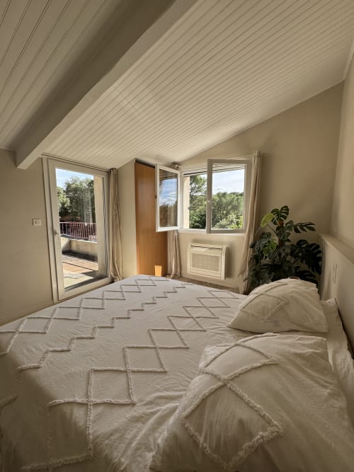 Chambre lumineuse à la villa d'Aniane avec lit queen-size, vue sur le jardin et portes-fenêtres donnant sur terrasse privée