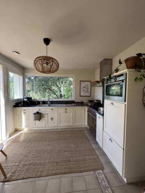 Cuisine moderne avec armoires crème, plan de travail noir et vue sur le jardin à la villa Domaine d'Olga à Aniane, France