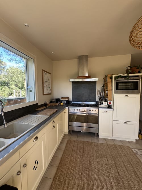 Cuisine moderne de la villa Domaine d'Olga à Aniane avec armoires crème, cuisinière inox et vue sur le jardin