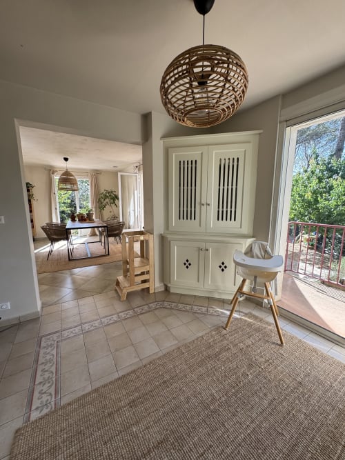 Séjour lumineux et contemporain avec suspension tissée, caissons crème et portes vitrées donnant sur le jardin du Domaine d'Olga