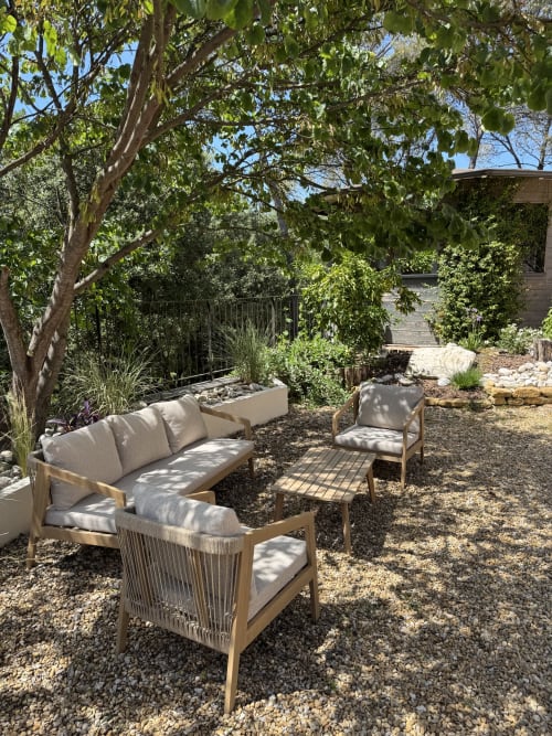 Coin détente ombragé de la villa Domaine d'Olga à Aniane avec mobilier bois et végétation luxuriante