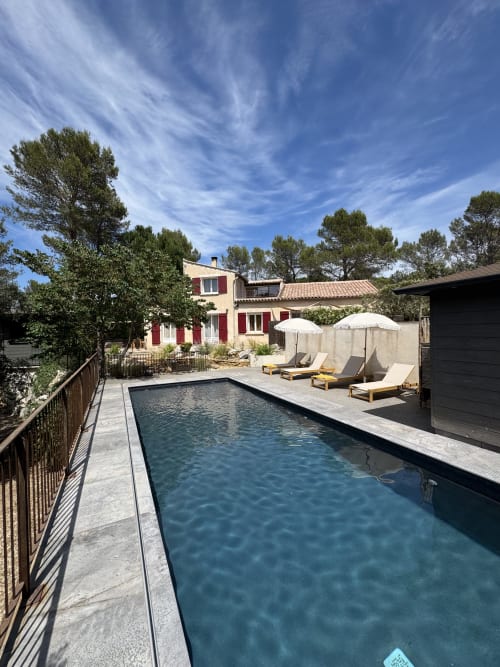 Villa Domaine d'Olga avec piscine rectangulaire, chaises longues, parasols et vue sur le jardin à Aniane, France