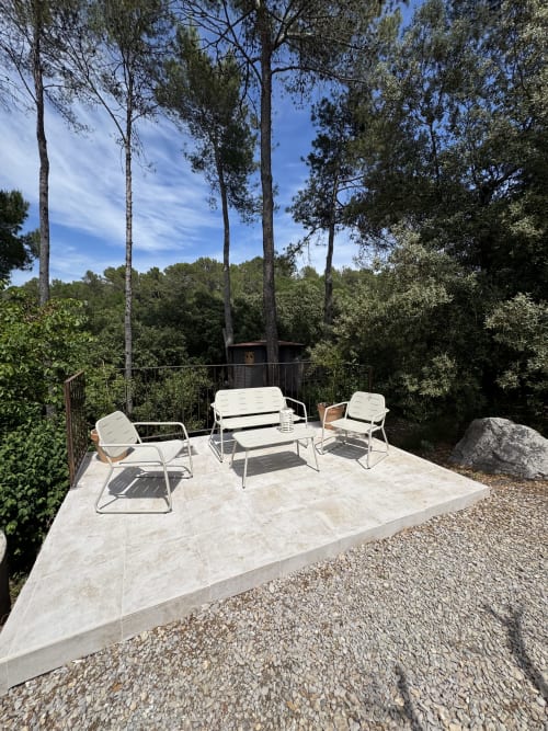 Espace de détente en plein air sur terrasse en pierre à la villa Domaine d'Olga à Aniane, entouré de grands pins et de jardins luxuriants