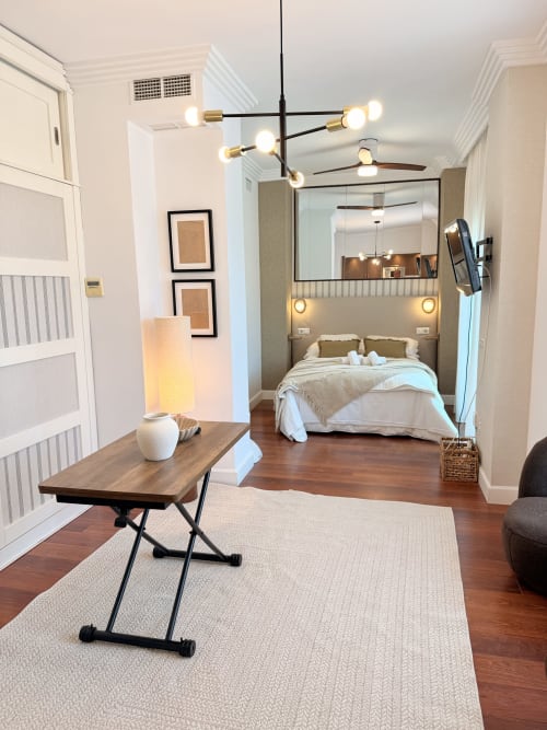 Moderno apartamento estudio en Málaga con dormitorio, zona de trabajo y sala de estar con suelos de madera y diseño contemporáneo
