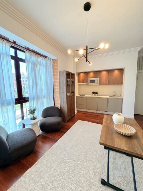 Moderno estudio en Málaga con sala de estar abierta, cocina integrada, mesa de comedor, mobiliario contemporáneo y vistas a la ciudad