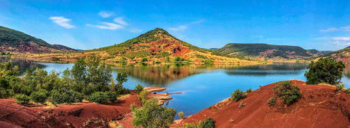 Vue pittoresque du lac avec collines de terre rouge et végétation luxuriante près du Domaine d'Olga à Aniane, France
