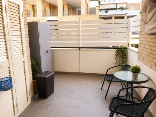 Modern apartment balcony in Roma with seating area, potted plants, and city views of Santa Andrea La Storta