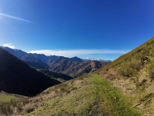 Paisaje de valle montañoso desde Casa Rural Posada Real de Pajares con laderas verdes, picos nevados y cielo azul despejado