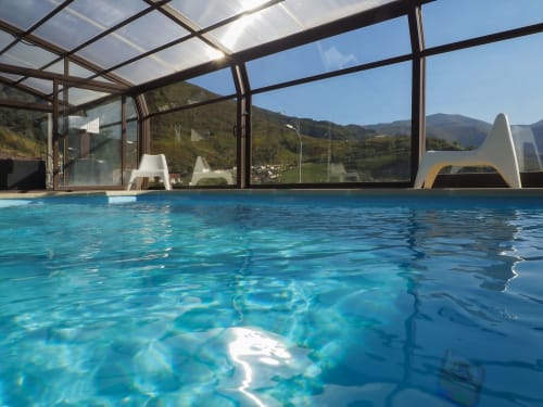 Piscina climatizada interior con vistas a la montaña en Casa Rural Posada Real, una casa de campo en Pajares, España