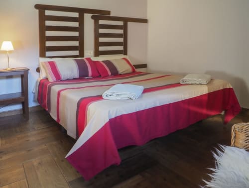 Dormitorio de Casa Rural Posada Real de Pajares con cama de rayas rojas, cabecero de madera y lámpara
