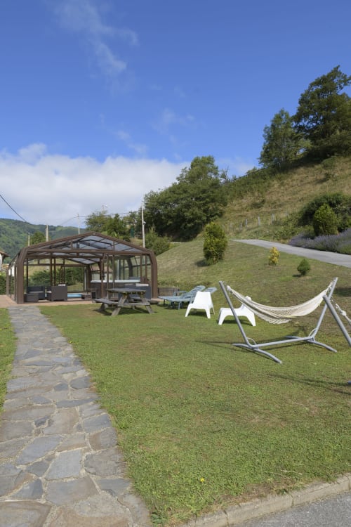 Jardín de Casa Rural Posada Real de Pajares con hamacas, mesa de picnic y pérgola marrón con vistas a ladera verde